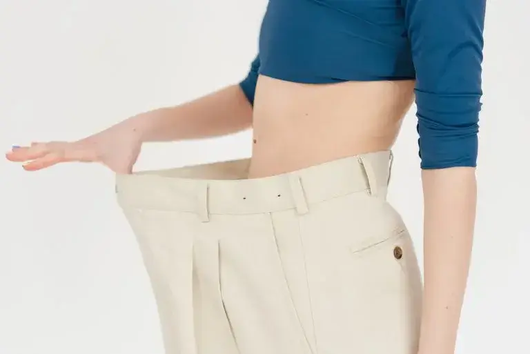 person holding waist band of pants away from stomach