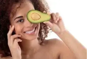 person smiling holding an avocado over eye